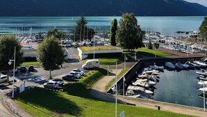 Un port de plaisance avec des bateaux, un espace de stationnement et une vue sur un lac, avec des montagnes en arrière-plan.