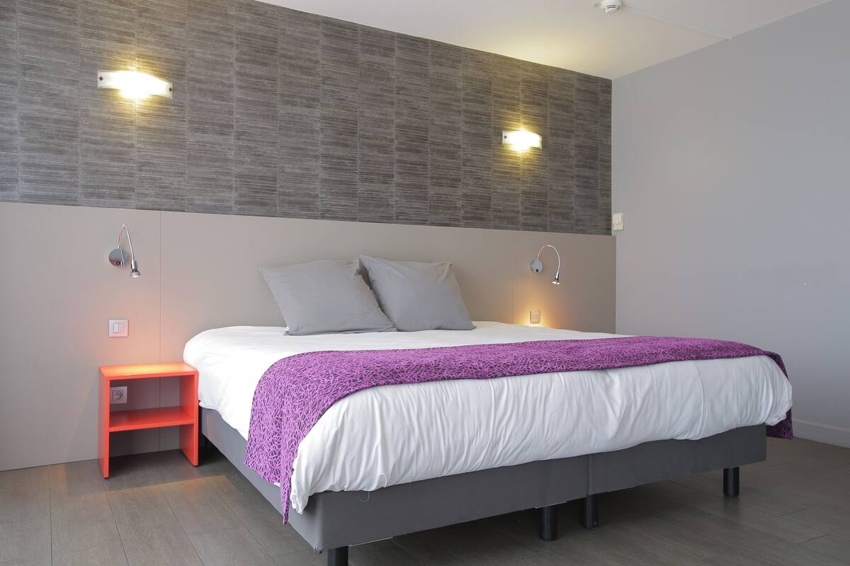 Een moderne slaapkamer met een bed, nachtkastjes en wandlampen.