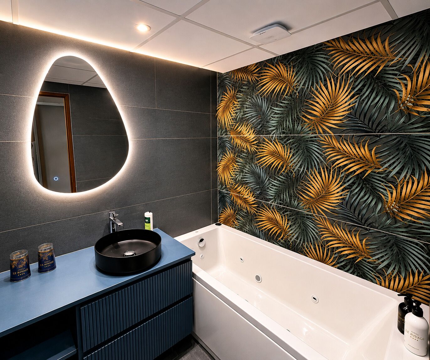 A modern bathroom with a round mirror, a bathtub, and a vanity with a dark countertop.