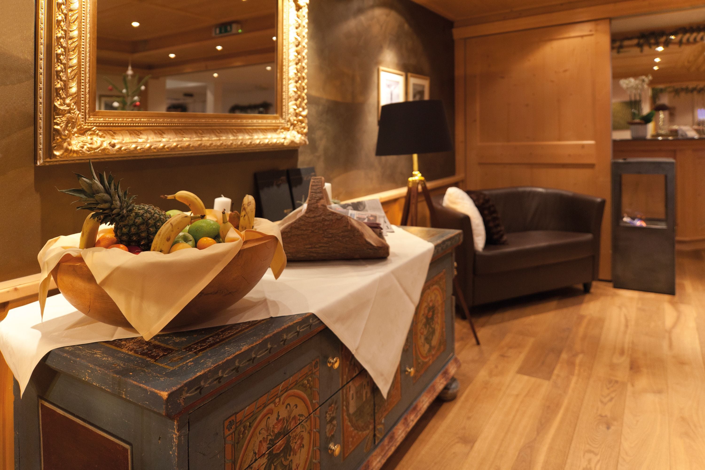 A wooden cabinet with a fruit bowl, a lamp, and a mirror in a hotel room.