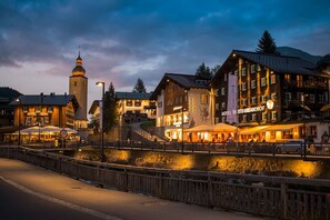 A hotel with a prominent tower, outdoor seating, and a mountain backdrop.