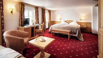 A hotel room with a bed, a desk, a chair, and a sofa.