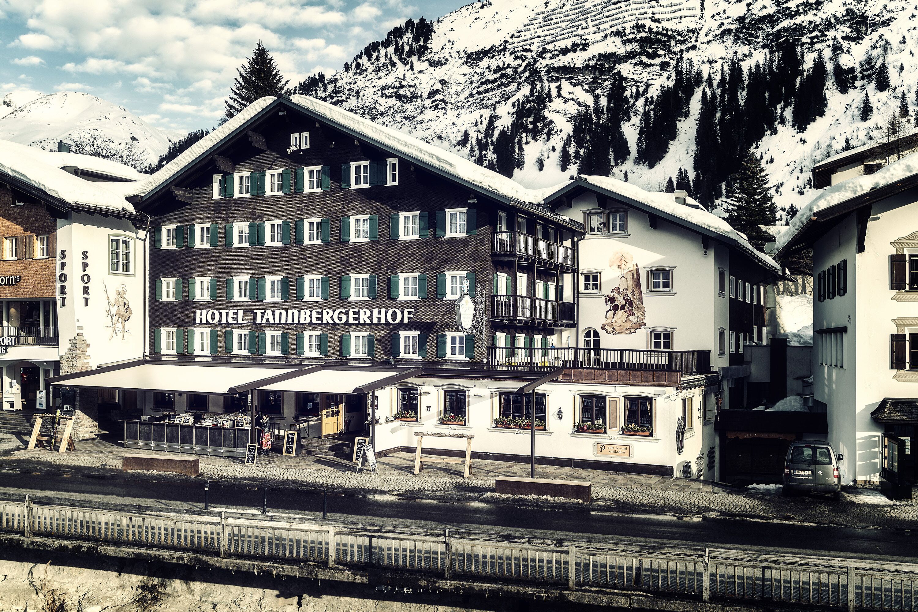 Un hotel con un cartel que dice "HOTEL TANNBERGERHOF" frente a un paisaje montañoso.
