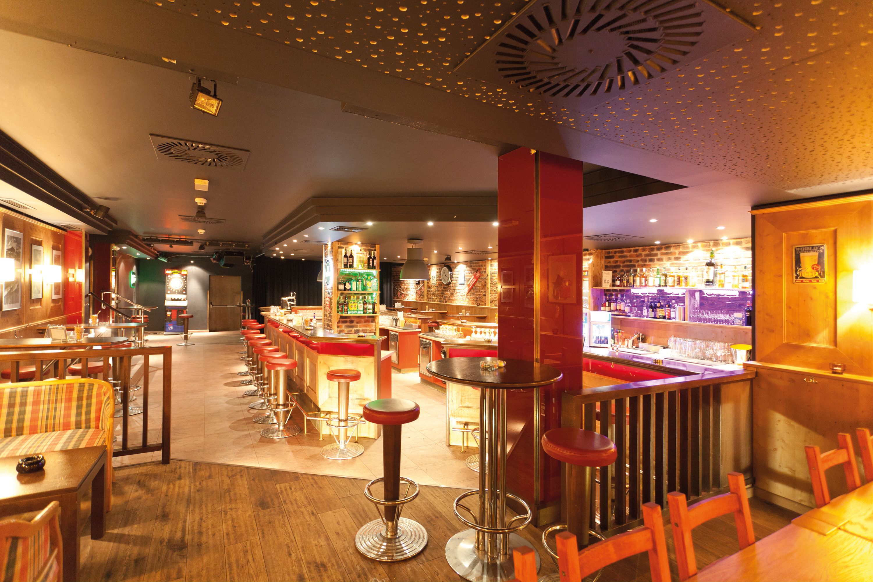 A bar area with stools, a counter, and shelves with bottles.