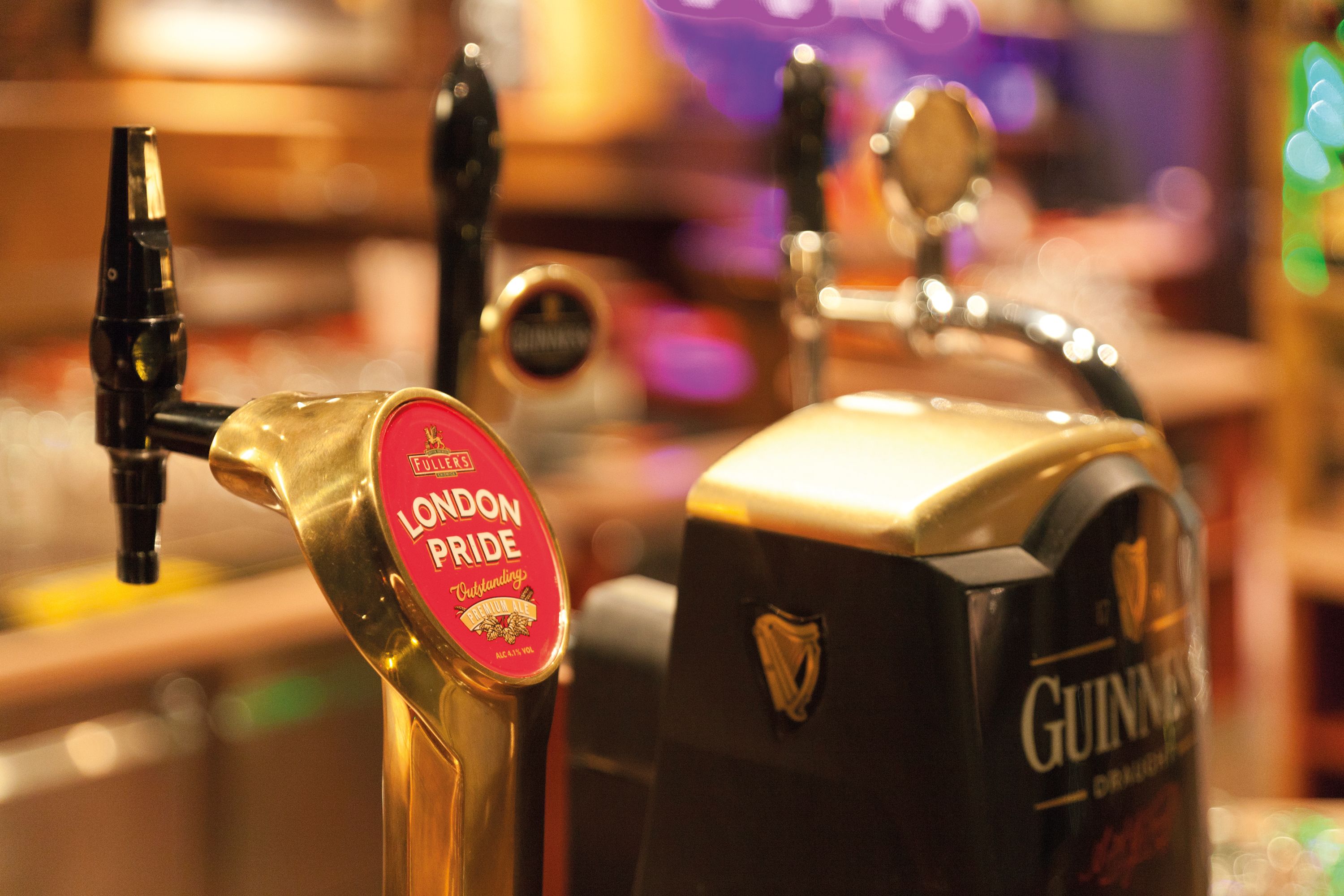Ein Hahn mit der Aufschrift "London Pride" und ein Hahn mit der Aufschrift "Guinness" in einer Bar.