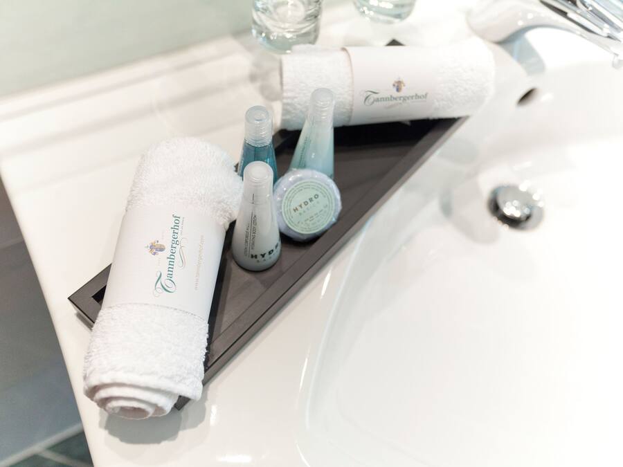 A bathroom sink with a white towel, a bottle of HYDRO, and a bottle of blue liquid.