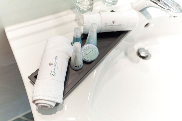 A bathroom sink with a white towel, a bottle of HYDRO, and a bottle of blue liquid.