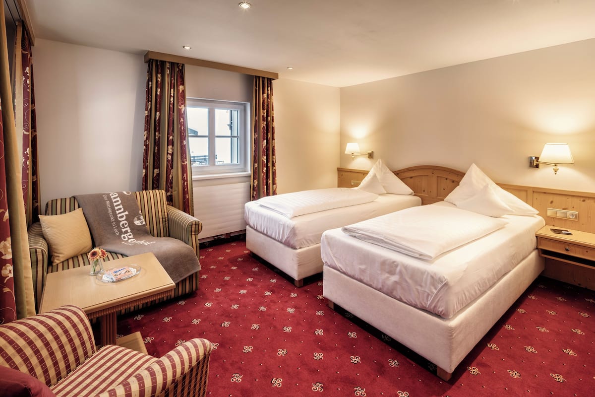 Habitación de hotel con dos camas, un sofá, una mesita y una ventana.