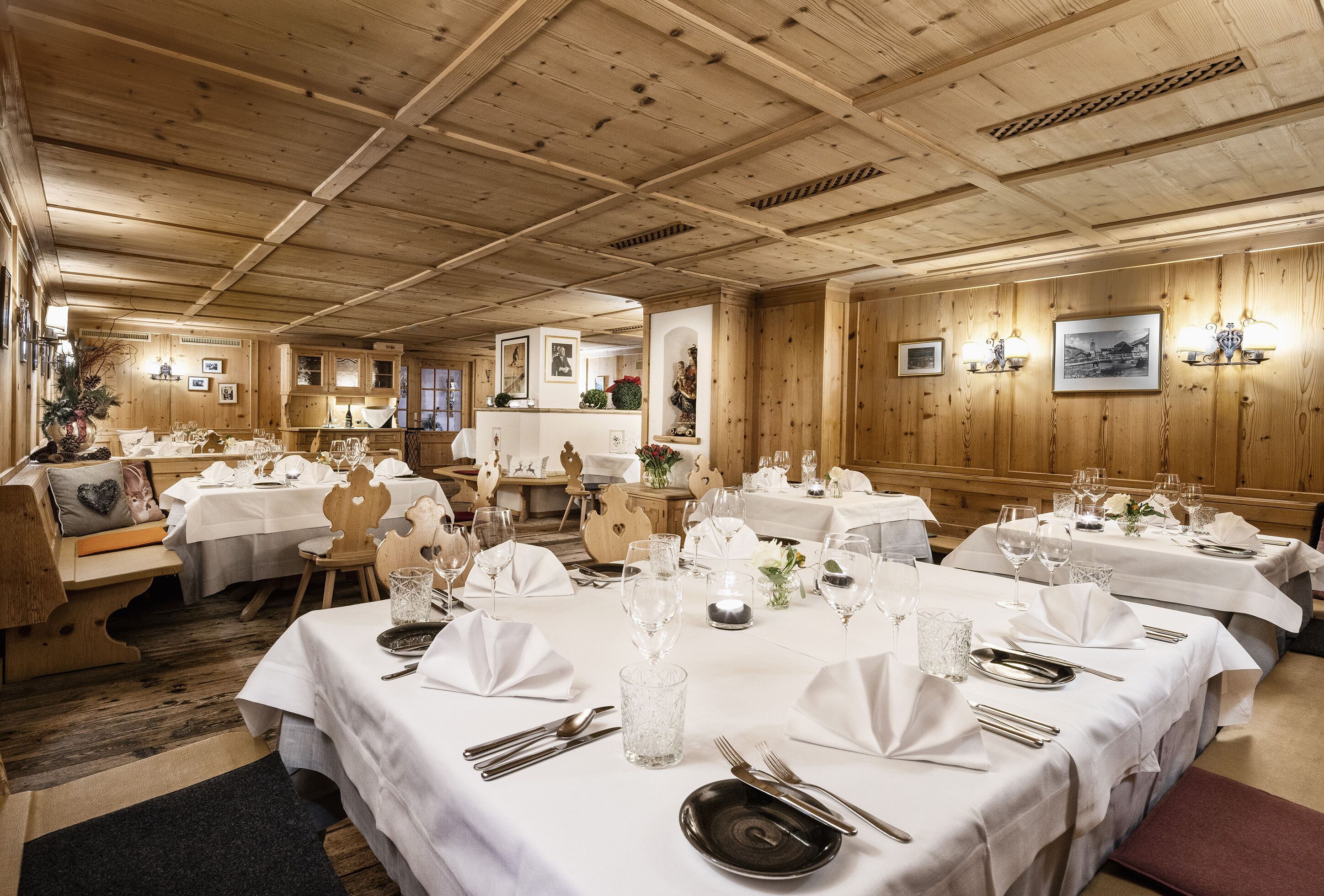 A restaurant with multiple tables set for dining, wooden paneling on the walls, and framed pictures on the walls.