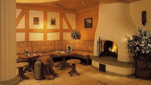 A cozy room with a fireplace, a sofa, a table, and a vase of flowers. - Bergheim (Lech am Arlberg)