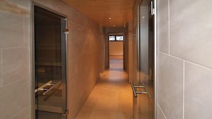A corridor with a glass door on the left, a metal handrail on the right, and a wooden ceiling. - Bergheim (Lech am Arlberg)