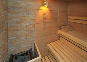 A sauna with wooden benches and a stone wall. - Bergheim (Lech am Arlberg)