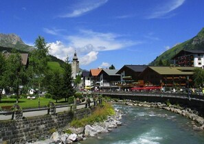 A riverside town with stone buildings, a church, and a bridge. - Bergheim (Lech am Arlberg)