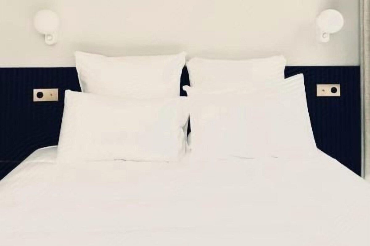 A bed with white bedding and two wall-mounted light fixtures.