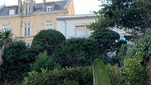 Un edifici gran d'estil arquitectònic clàssic, envoltat de vegetació densa i plantes tropicals.