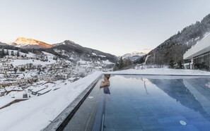 A person in a pool with a view of a snowy mountain town and buildings. - Rainell Dolomites Retreat (Castelrotto)
