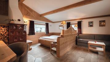 A rustic room with a wooden bed, a sofa, a small table, and a stone fireplace.