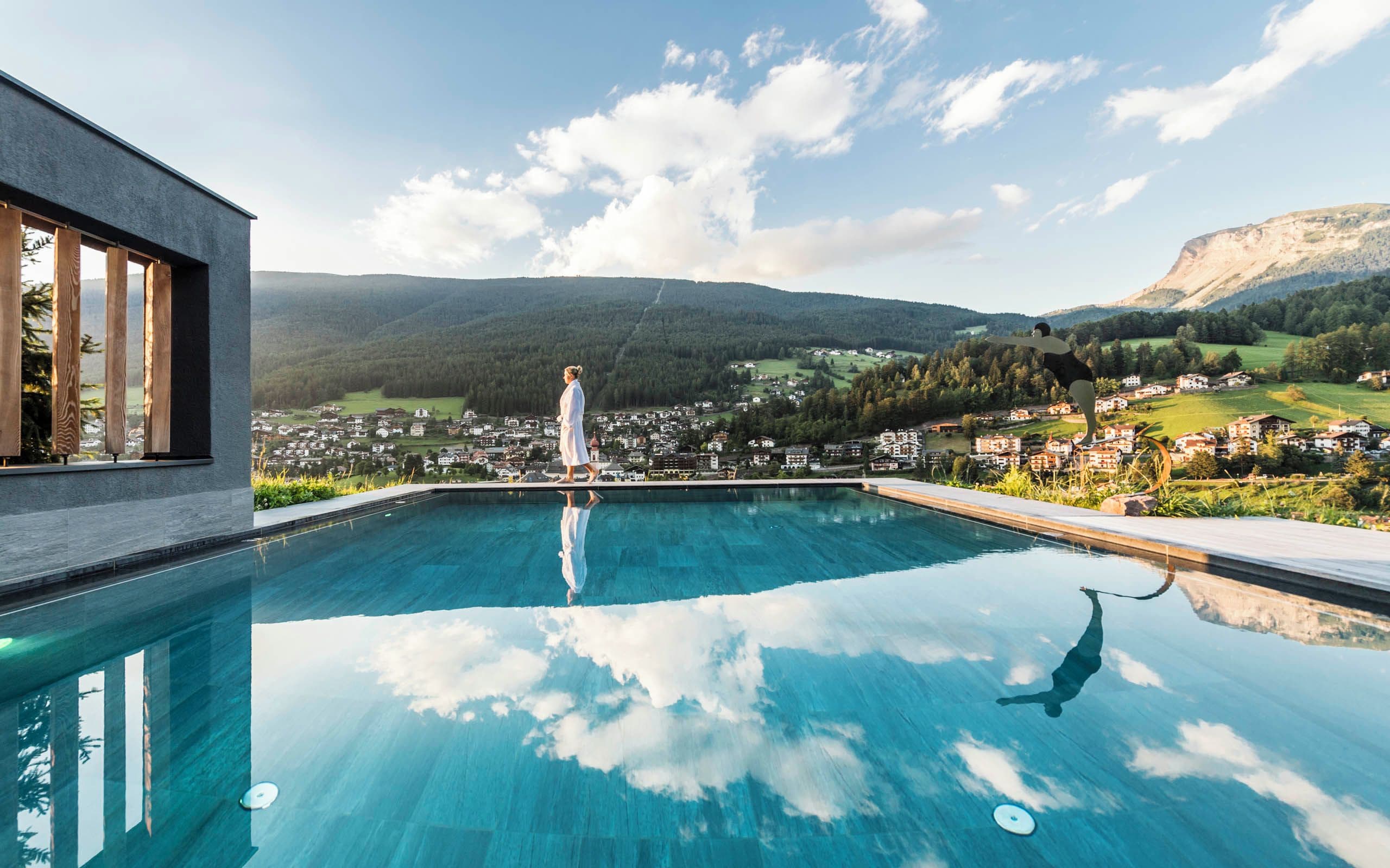Una piscina con vistas despejadas a un pueblo y montañas al fondo.