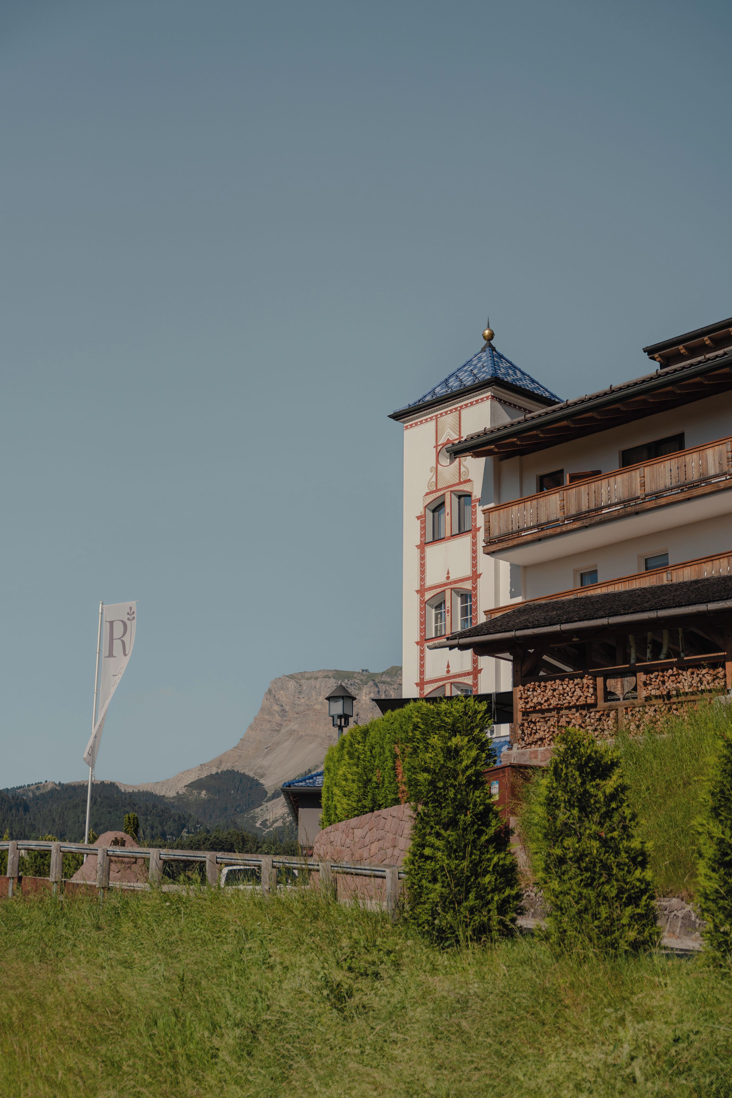 Un edificio con una torre, un balcón y una montaña al fondo.