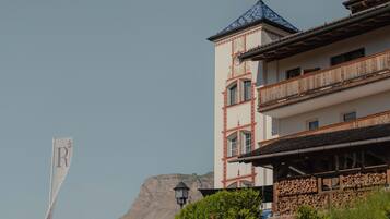 Un edificio con una torre, un balcón y una montaña al fondo.