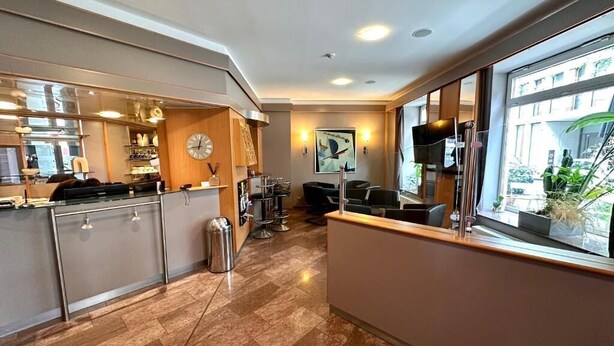 A modern kitchen with a central island, a dining area with chairs, and a large window with a view of the outside. - Insel Hotel (Cologne)