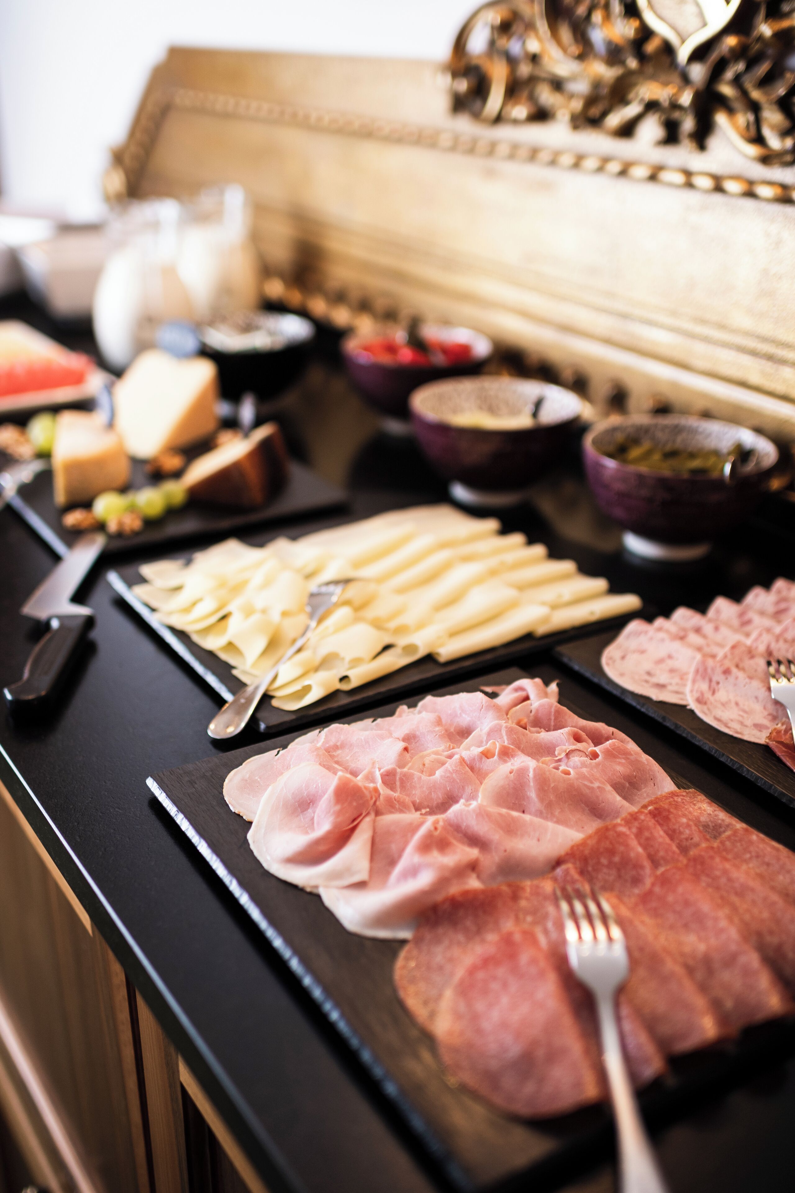 A buffet table with various food items including pasta, meats, and cheeses.