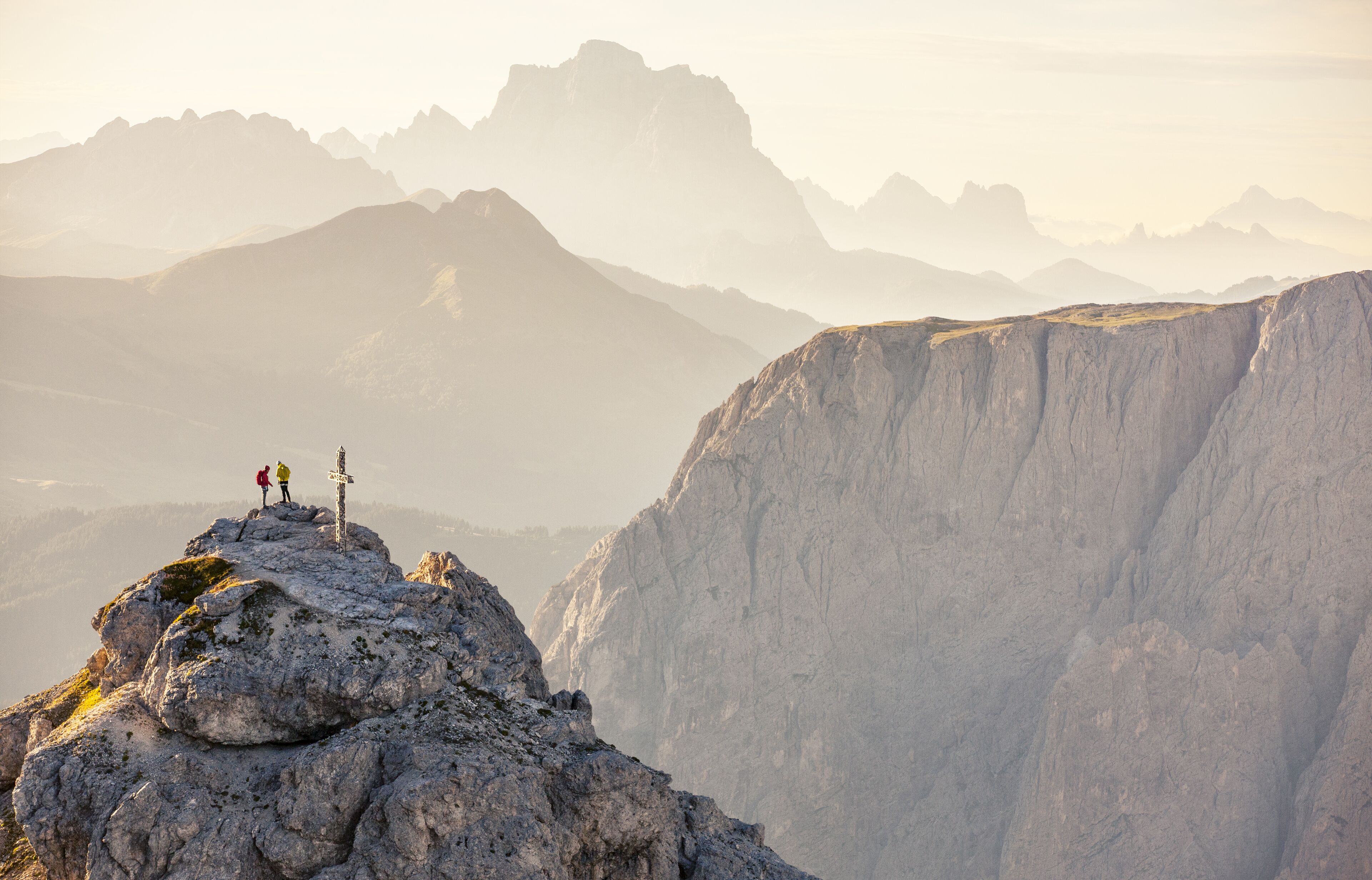 A mountain landscape with rocky terrain and two people standing on a peak.