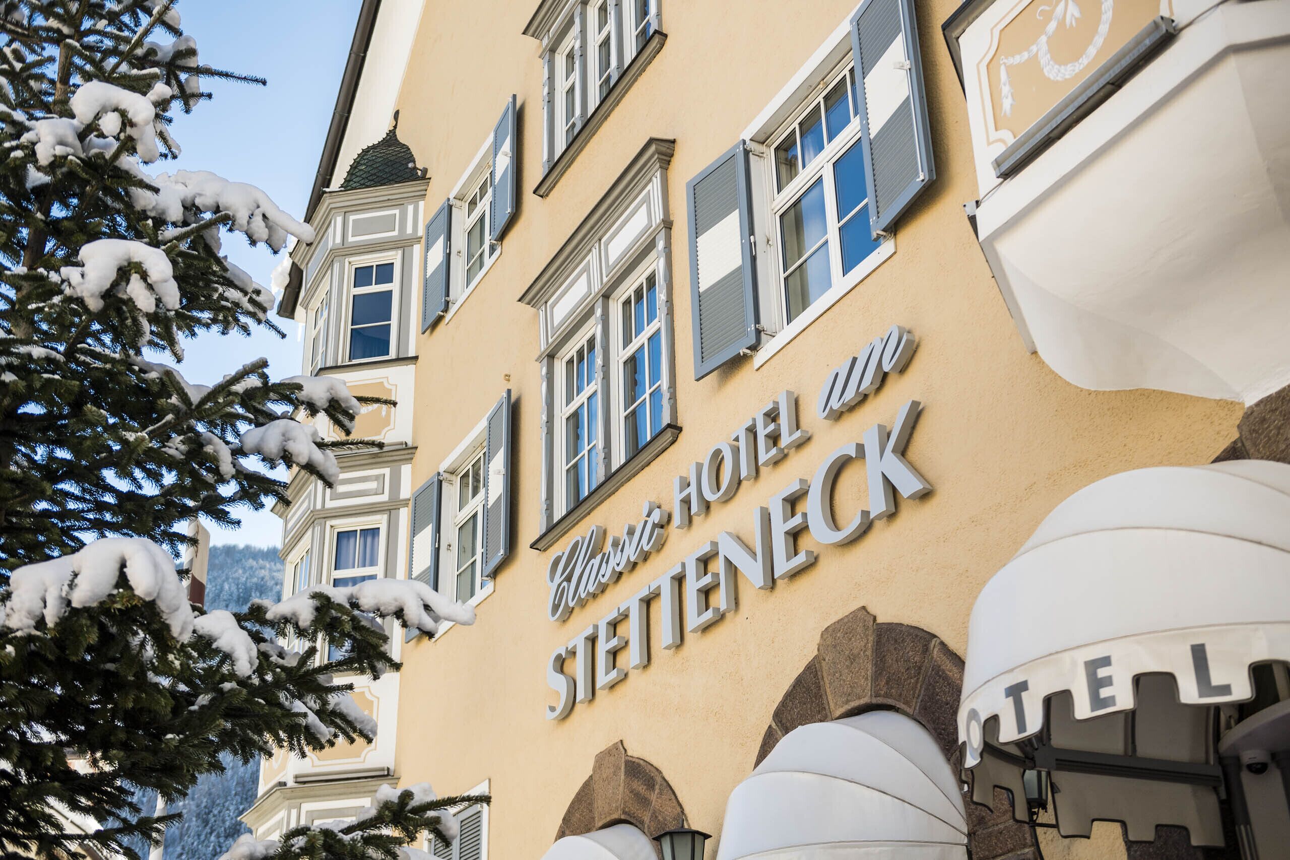 The exterior of the Classic Hotel Stettenbeck with snow-covered trees and a clear sky.