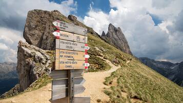 A directional signpost on a mountain trail with multiple destination labels.