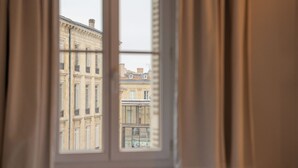A view through a window with a view of a building with multiple windows and balconies. - Hotel des Grands Hommes - Bordeaux Centre (Bordeaux)