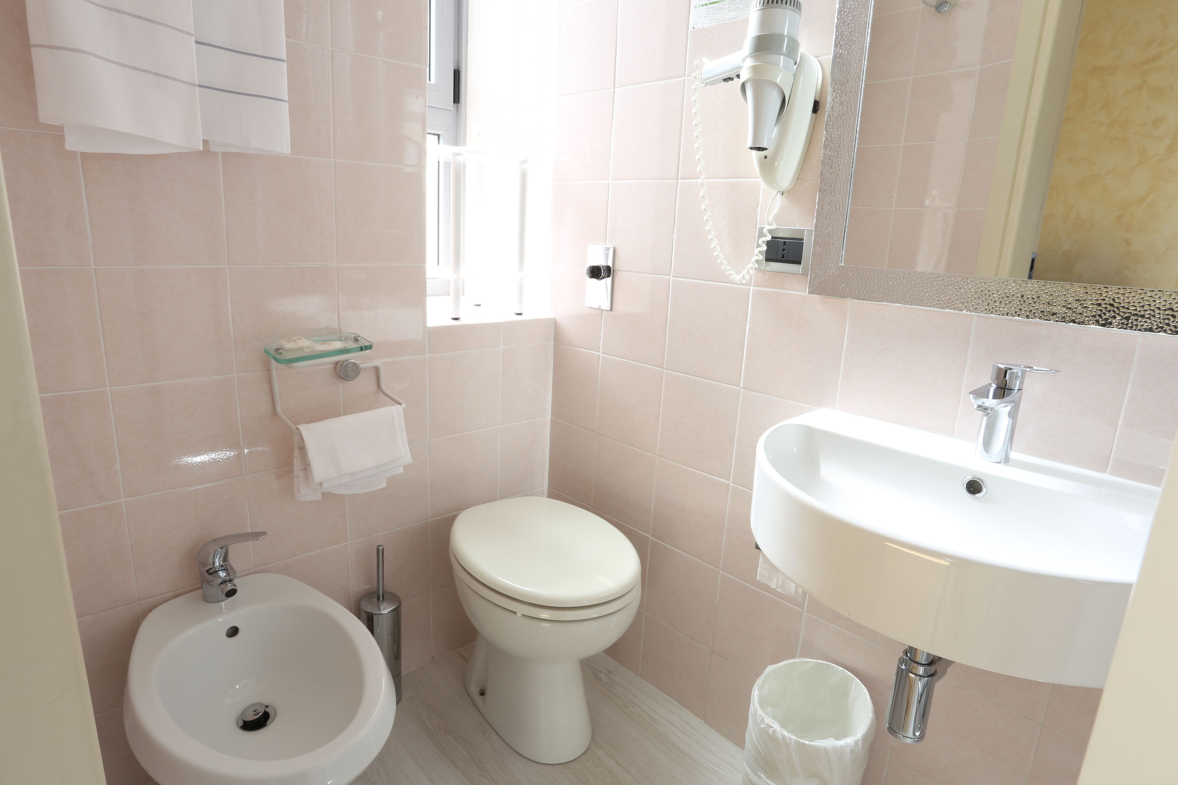 Une salle de bain équipée d’un bidet, de toilettes, d’un lavabo et d’un miroir.