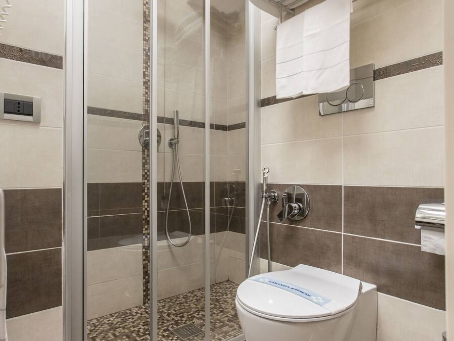Un baño con ducha de mampara de vidrio, inodoro y un perchero para toallas.