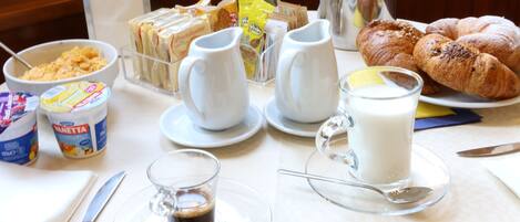 A breakfast table with various food items, including croissants, a glass of milk, and a coffee cup.