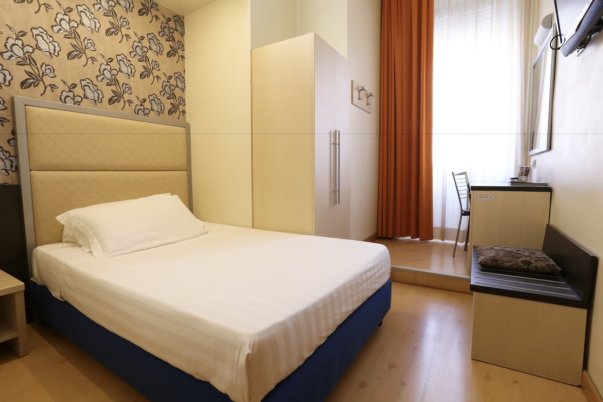 A bedroom with a bed, wardrobe, desk, and chair.