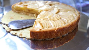 A pie with a caramelized top, placed on a glass plate with a metal serving utensil. - Hotel Piacenza (Milan)