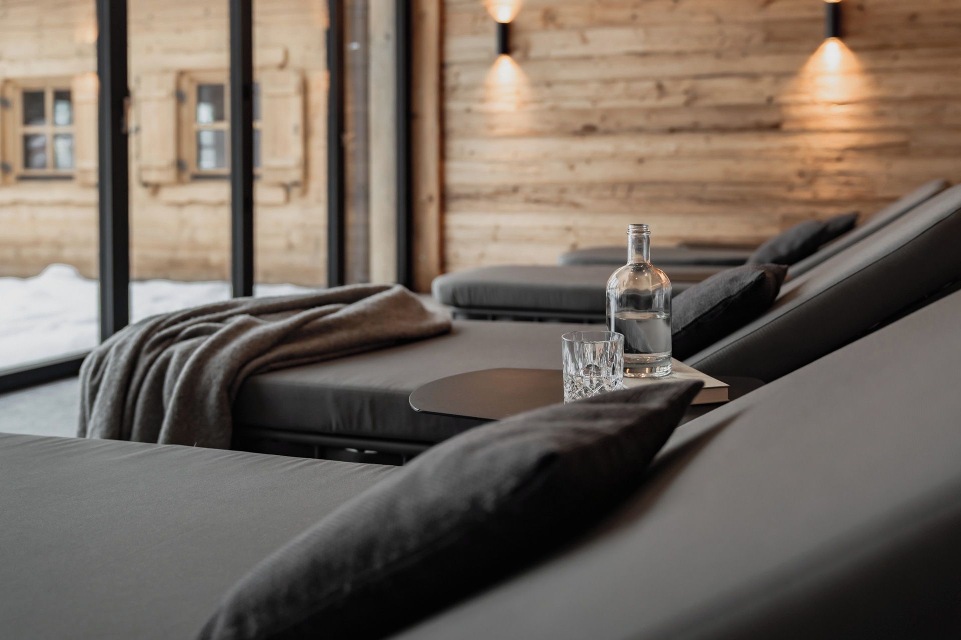 En modern inredning med en soffa, ett glas vatten och en flaska på ett bord.