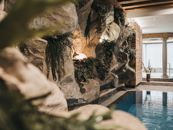 A pool area with a rocky wall adorned with various plants. - VAYA Achensee (Achenkirch)
