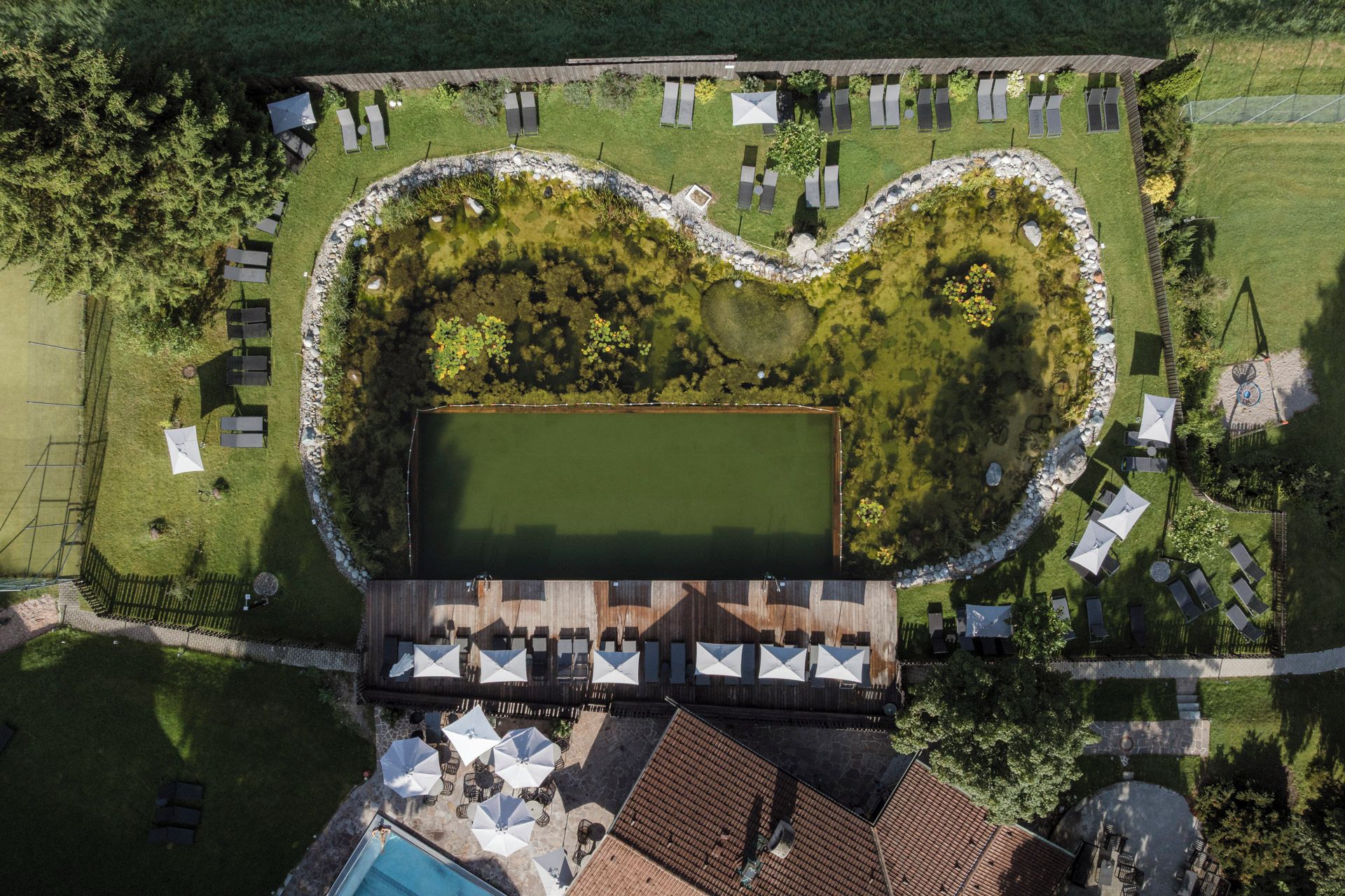 Vista aérea de una propiedad con un estanque con forma de corazón, zonas de estar al aire libre y una piscina.