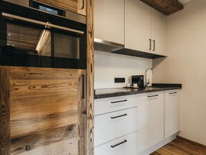 Una cocina moderna con armarios blancos, un microondas negro y una pared de acento de madera.