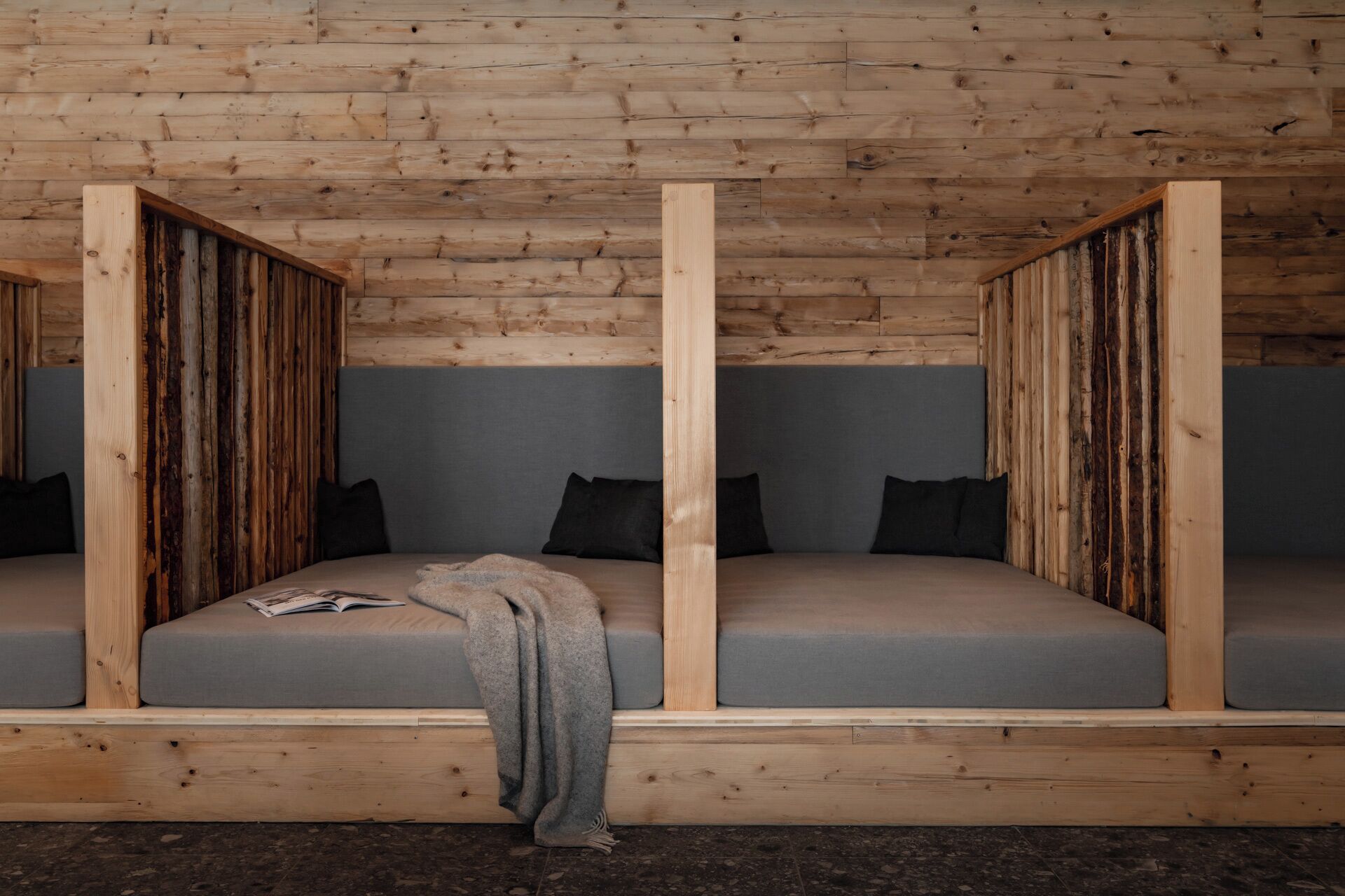 A wooden cabin with two built-in beds, each with grey bedding and black pillows.