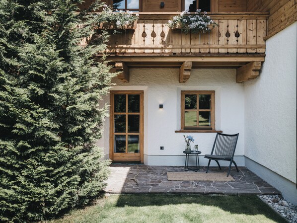A wooden balcony with a stone floor, a door, and a window. - VAYA Achensee (Achenkirch)