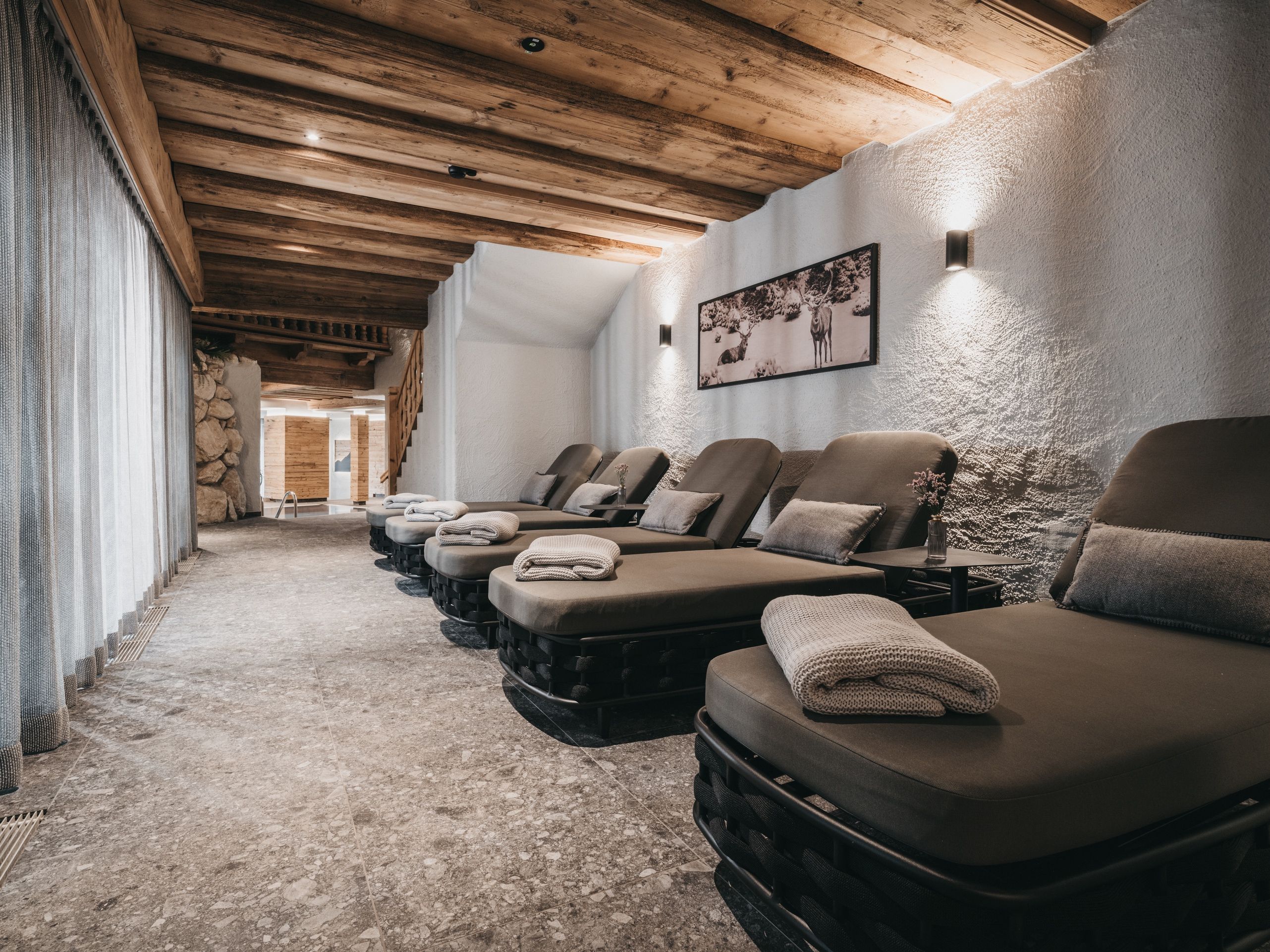 A spa room with multiple massage chairs, a stone wall, and a wooden ceiling.