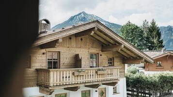 Eine Holzchalet mit Balkon, im Hintergrund ein Berg und ein klarer Himmel.