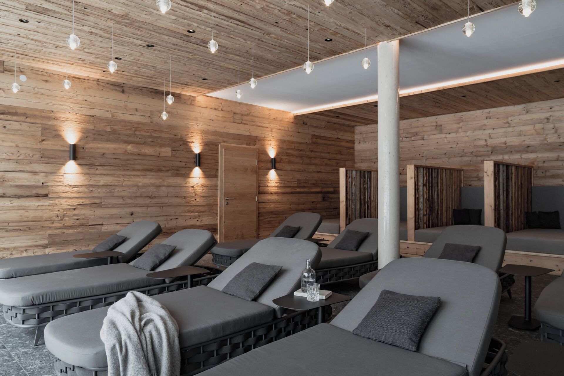 Ett spa-rum med träväggar, flera massagebänkar och hängande lampor.