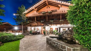 A large wooden building with a stone courtyard, multiple balconies, and hanging flower baskets. - VAYA Achensee (Achenkirch)