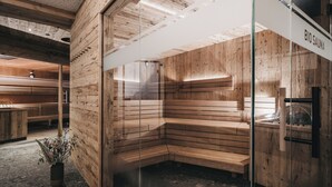 A sauna room with wooden walls and benches, a glass partition, and a sign reading "BIO SAUNA". - VAYA Achensee (Achenkirch)