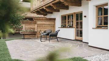 Eine Terrasse mit Steinplattenboden, Holzmöbeln und einem Holzzaun mit Blumenkästen.