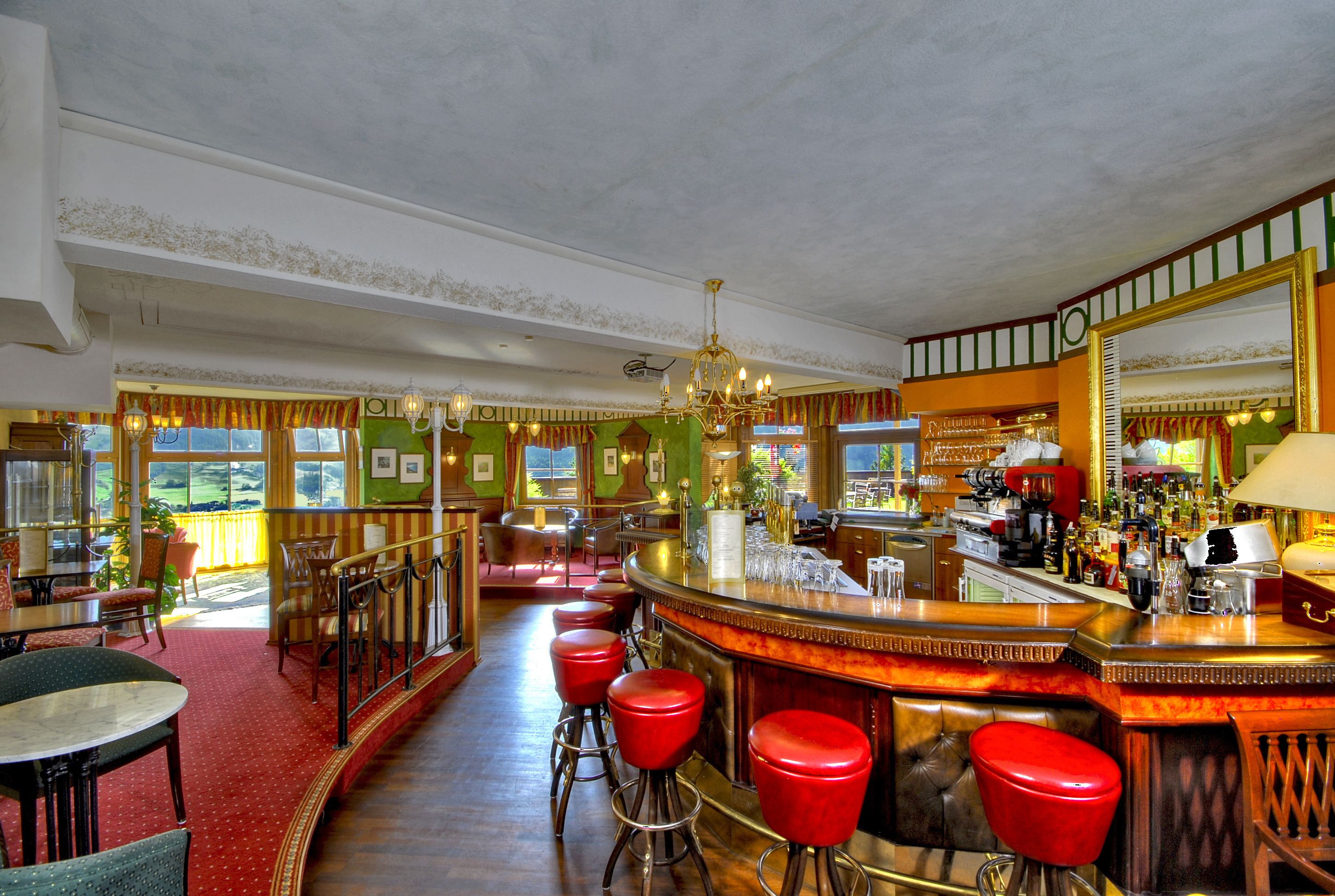 A bar area with a counter, stools, and a large mirror.