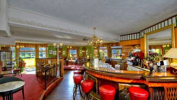 A bar area with a counter, stools, and a large mirror.
