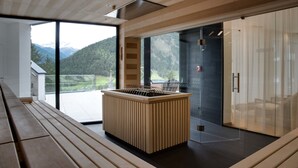 A modern interior with a wooden bench, a central island, and a glass partition. - Hotel Goldried (Matrei in Osttirol)